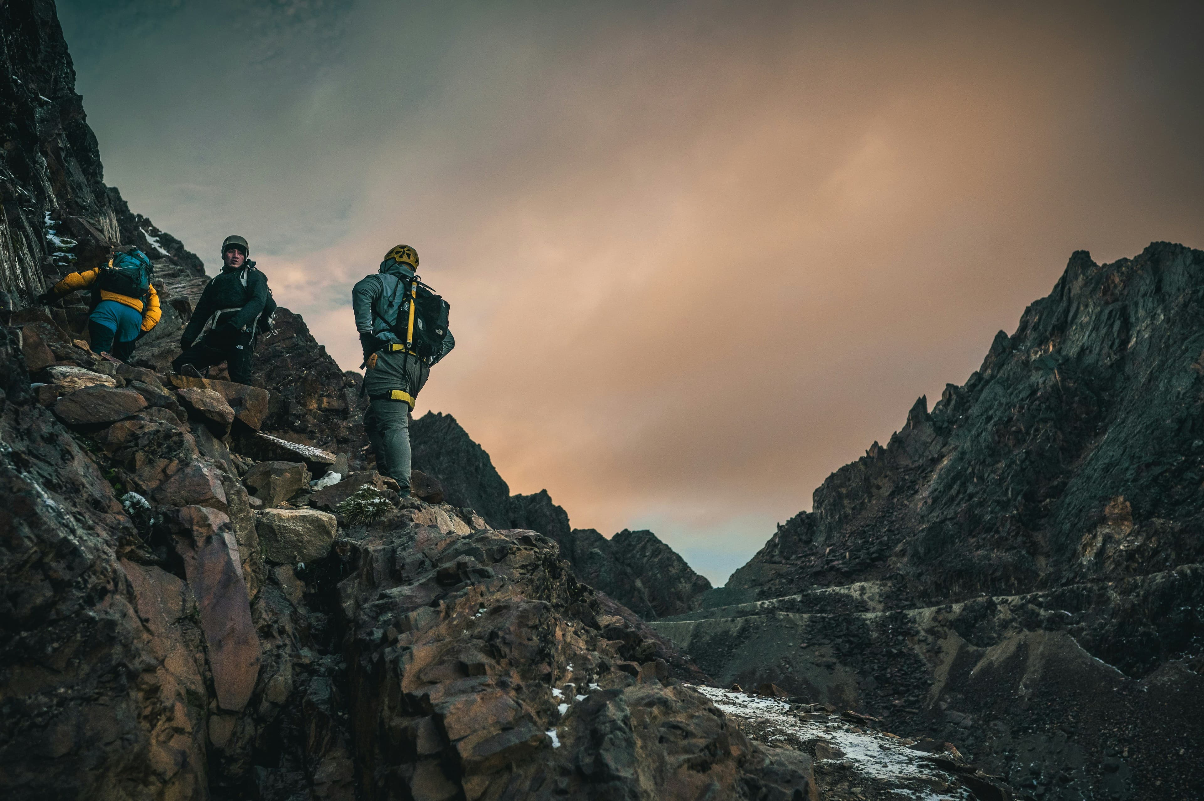 adventurers-climb-a-rocky-mountain-under-a-cloudy-sky
